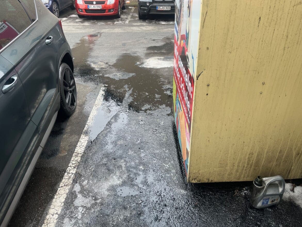 Ölspur auf dem Parkplatz des Supermarkts.