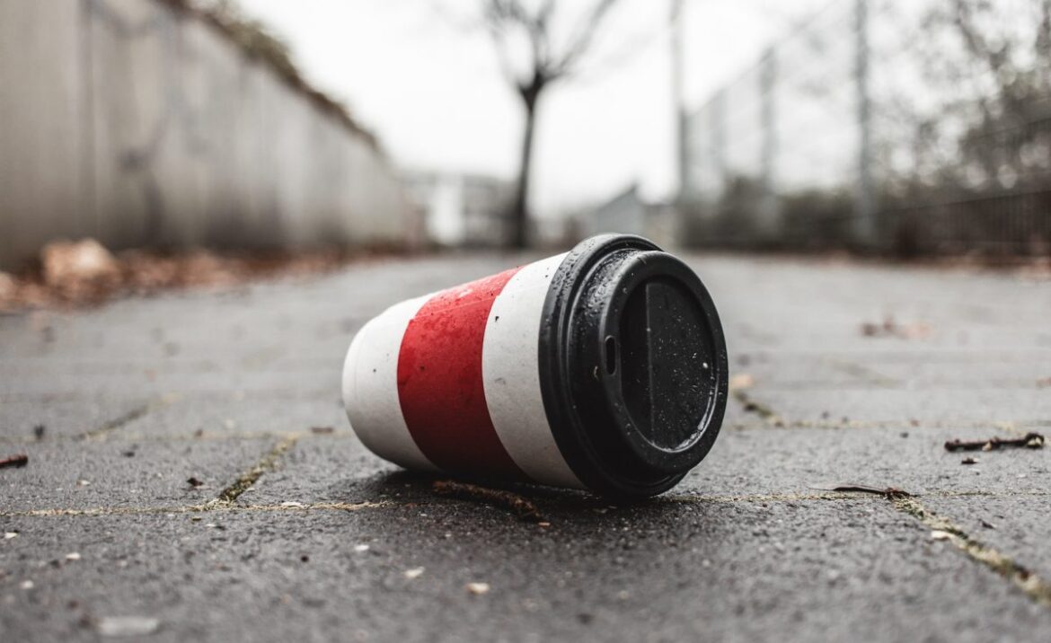 Weggeworfener leerer Kaffeebecher liegt auf Gehweg.