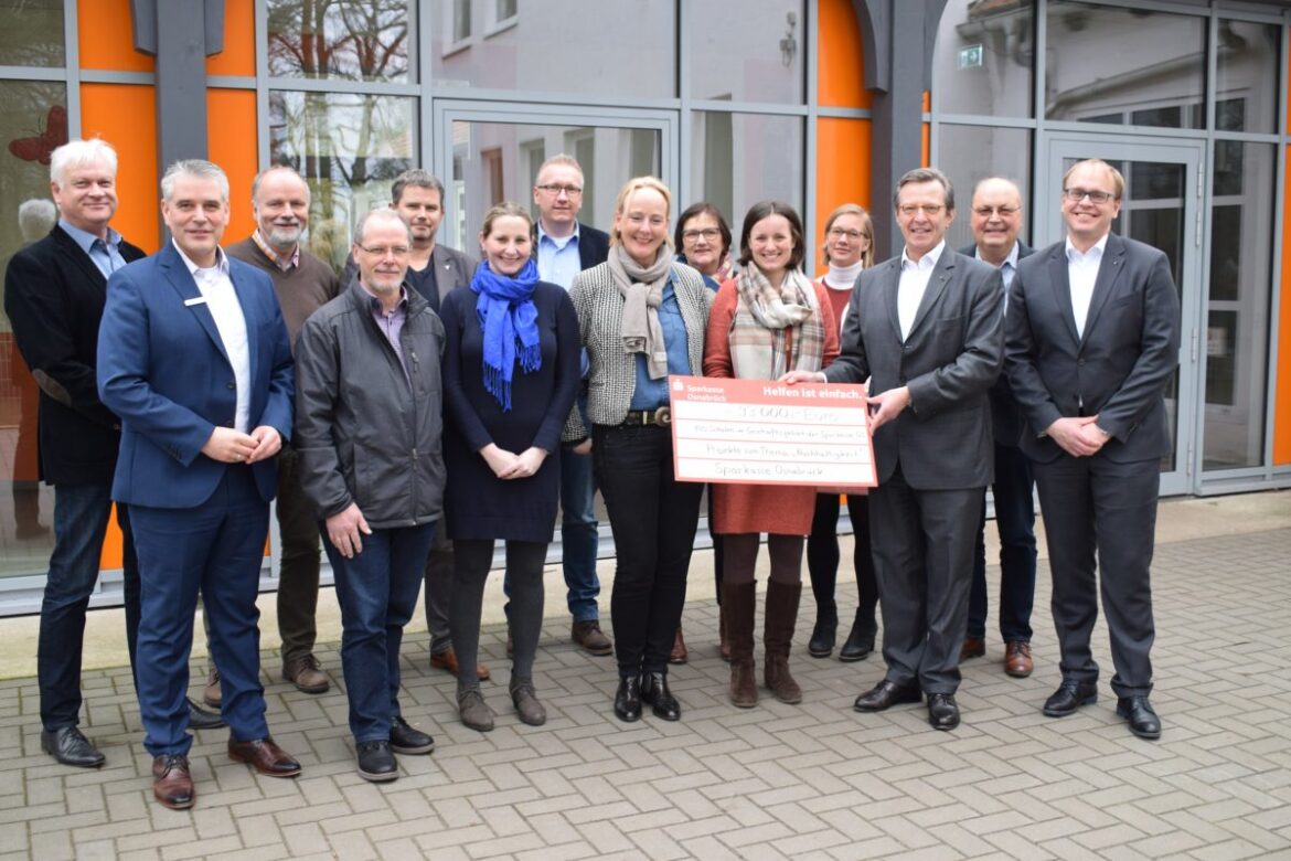 Die Sparkasse übergibt einen Symbolischen Scheck an die Vertreter der Schulen