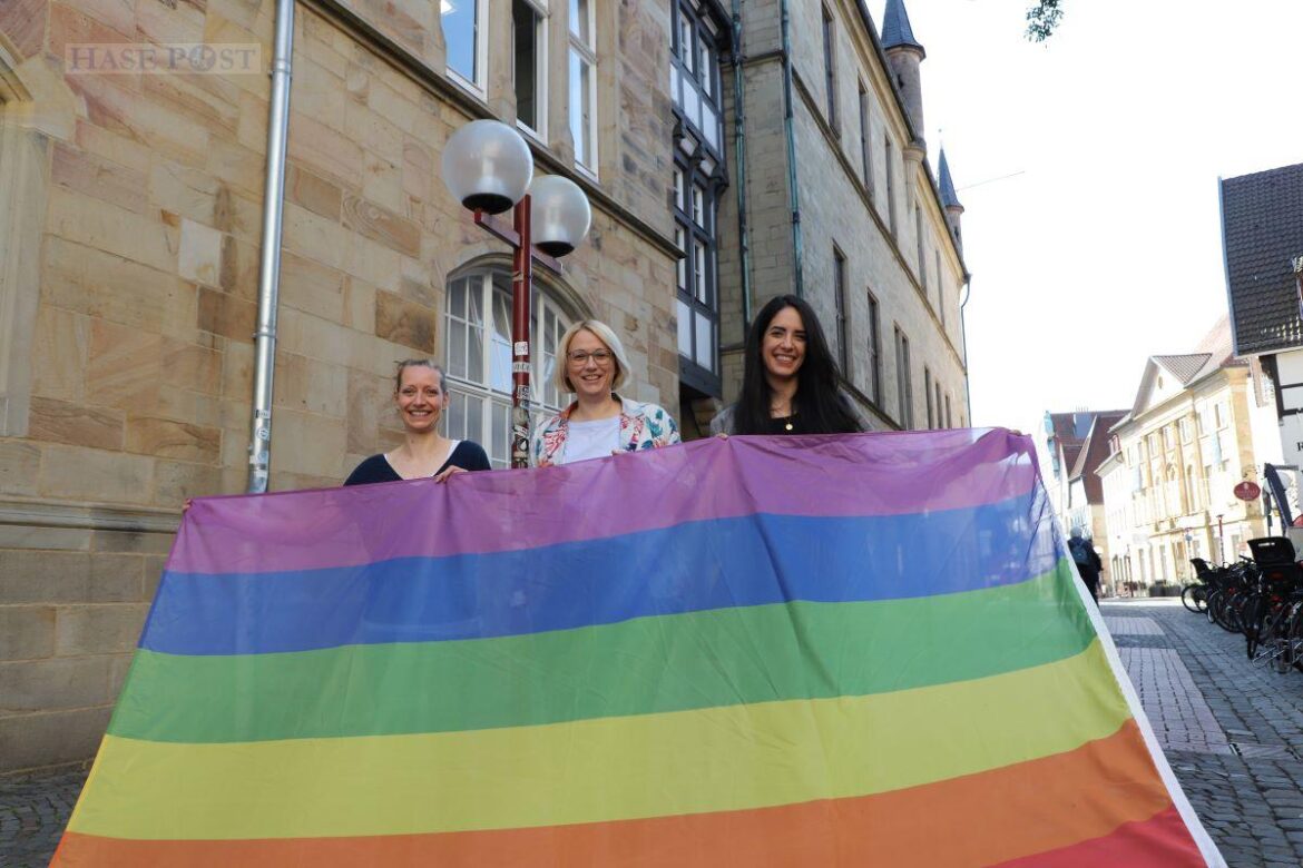 Ann Kristin Schneider, stellvertretende Gleichstellungsbeauftragte (links), Oberbürgermeisterin Katharina Pötter und Heba Najdi vom Antidiskriminierungsbüro der Stadt Osnabrück mit der Regenbogenflagge, die am Dienstag, 17. Mai, am Rathaus weht. / Foto: Nina Hoss (Stadt Osnabrück)
