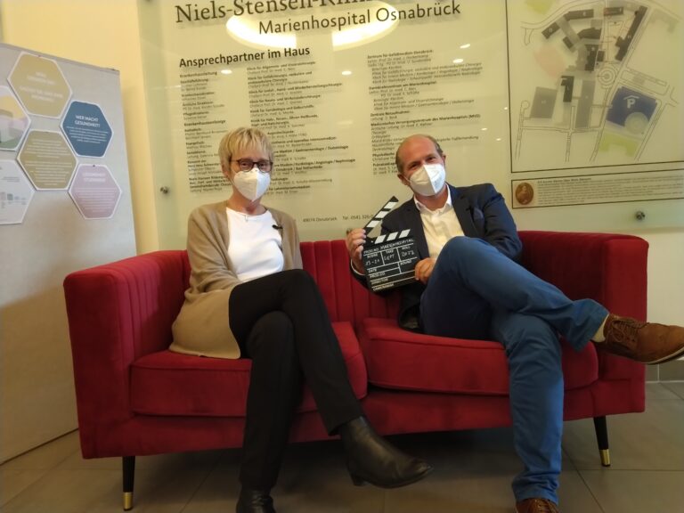 MHO-Pflegedirektorin Susanne Karrer und Koordinator des Gesundheits-Campus Osnabrück Dr. Daniel Kalthoff sitzen auf dem roten Sofa. / Foto: Julian Tischer