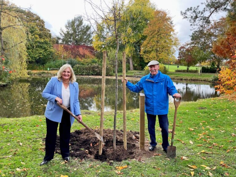 Bürgermeisterin Dagmar Bahlo und Dieter Michalowitz beim Einpflanzen des Tupelobaums am Ufer des Schwanenweihers. / Foto: Stadt Georgsmarienhütte (Niklas Otten)
