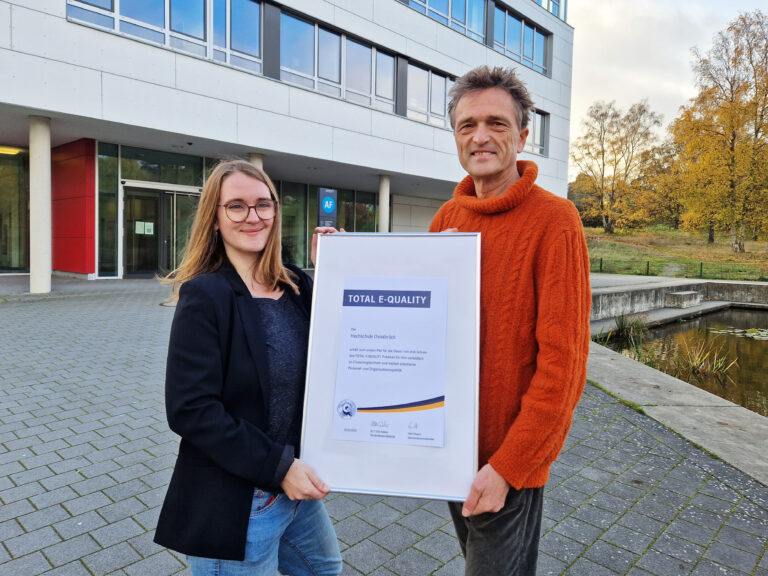 Die Referentin der zentralen Gleichstellungsbeauftragen der Hochschule Osnabrück, Berit Blawert, freut sich mit Hochschulpräsident Prof. Dr. Andreas Bertram über das Prädikat TOTAL-E-QUALITY. Dieses zeichnet die Hochschule für ihre vorbildliche an Chancengleichheit orientierte Personal- und Organisationspolitik aus. / Foto: Hochschule Osnabrück