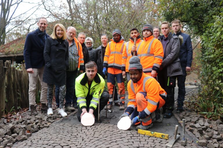 Bildunterschrift: V.l.n.r.: In gemeinsamer Arbeit entsteht der Elephant Walk of Fame: Sebastian Benstein (Zoo Osnabrück), Heike Busemann (Zoo Osnabrück), Friedrich Pfohl (Dieckmann), Ralf Grafunder (KME), Andreas Busemann (Zoo Osnabrück), Lars Schönball (KME) sowie Jens-Peter Zuther (Dieckmann; 3.v.r.) zusammen mit den Auszubildenden der Firmen Dieckmann Bauen + Umwelt sowie KME Germany. / Foto: Zoo Osnabrück (Hanna Räckers)