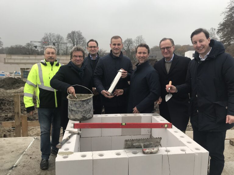 Osnabrücker Stadtbaurat Frank Otte (Zweiter von links), Architekt Phillip Schneider (Dritter von links), Verkaufsmanagement Barings Nikolas von Kleis (Vierter von links) und Anima Projektleiter Dr. Mark Maurin (ganz rechts) sowie andere Beteiligte platzieren die Zeitkapsel während der Grundsteinlegung. / Foto: Burrichter