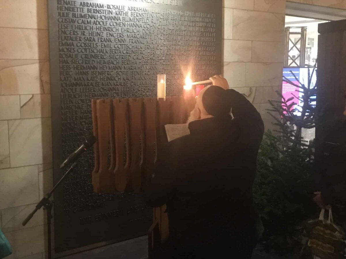 Kantor Baruch Chauskin zündet die dritte Chanukka-Kerze vor der Gedenktafel an der Stadtbibliothek an. / Foto: Burrichter