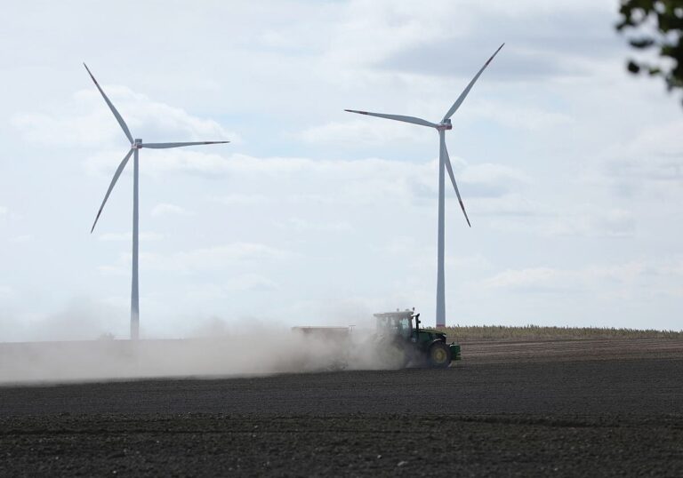 Windräder und ein Traktor auf Ackerfläche