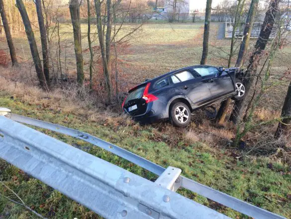 abgestürzter PKW zwischen Böschung und Bäumen