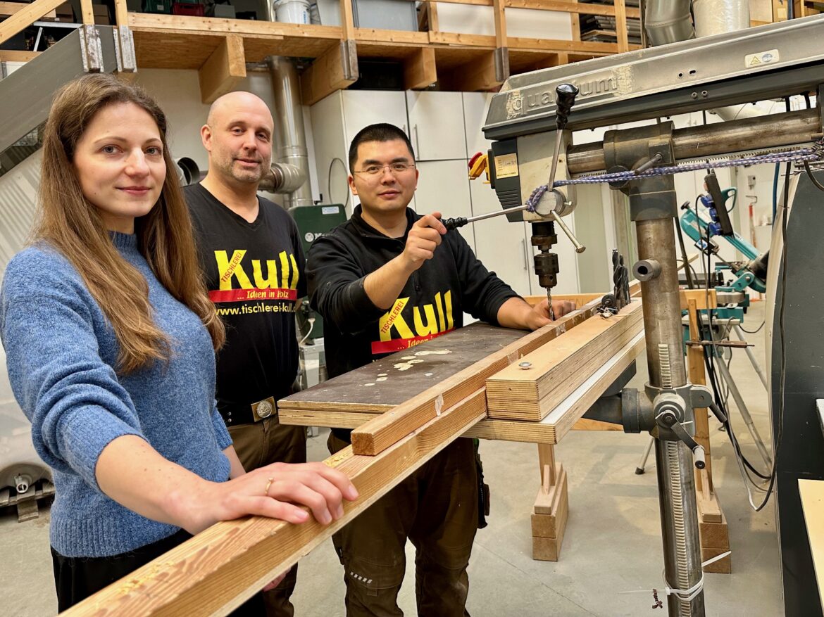 Victoria Fründ vom WIGOS-Fachkräftebüro (v. li.) und Markus Kull, Geschäftsführer der Tischlerei Kull, freuen sich, dass sich „Karl“ in seiner neuen Heimat so gut eingelebt hat. / Foto: Sandra Joachim-Meyer