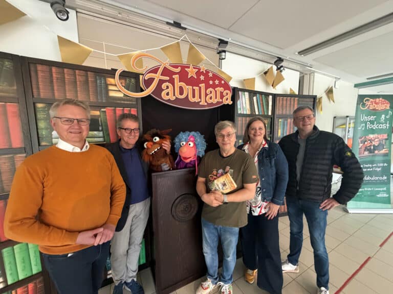 Ludger Flohre (Westenergie), Bürgermeister Guido Halfter, Ruth Brand (Westenergie) und Peter Band (Public Entertainment AG) (v.l.) begrüßten Jürgen „Yogi“ Eick und die Puppen „Baba Book“ und „Laila Musica“ (Mitte) in der Grundschule Bissendorf. / Foto: Gemeinde Bissendorf in Bissendorf (Ort)