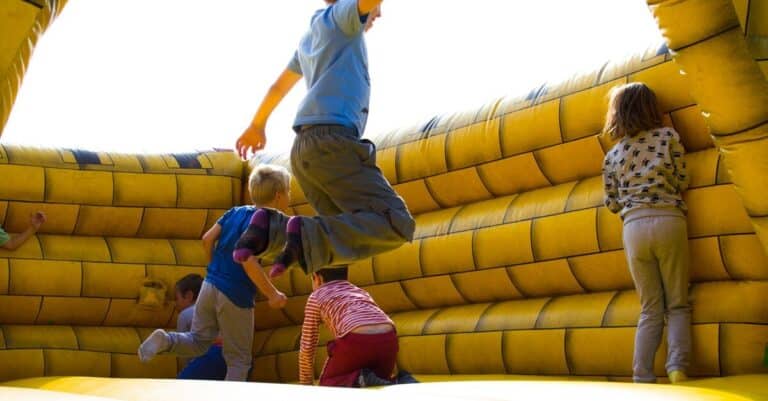 Kids enjoying a fun time bouncing in a vibrant inflatable castle outdoors.
