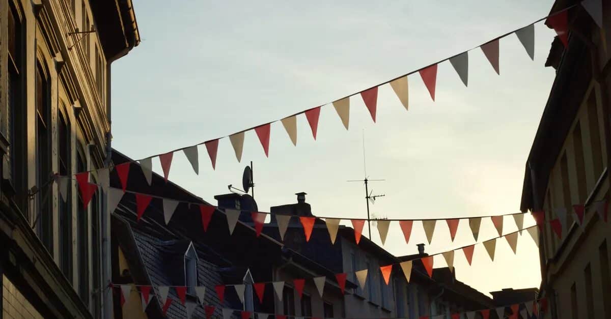Bunte Wimpelketten schmücken eine ruhige europäische Gasse im warmen Abendlicht.