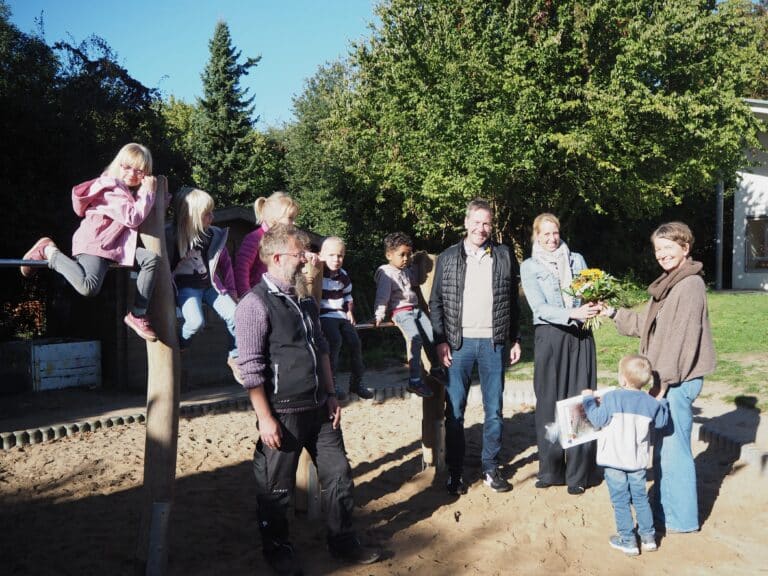Silke Peters (rechts) und die Kinder der Kita St. Katharinen bedanken sich bei Thorsten und Anke Janssen von der Adda-Heywinkel-Stiftung (Mitte) und Sven Kalinowski von RöKa GartenSpiel (links). / Foto: Kita St. Katharinen in Wüste