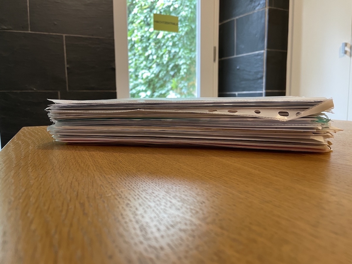Ein ganzer Stapel Unterlagen liegt vor Ramona S. auf dem Tisch der HASEPOST-Redaktion. Zusammen erzählen die Dokumente die Geschichte einer jahrelangen Odyssee. / Foto: Dominik Lapp