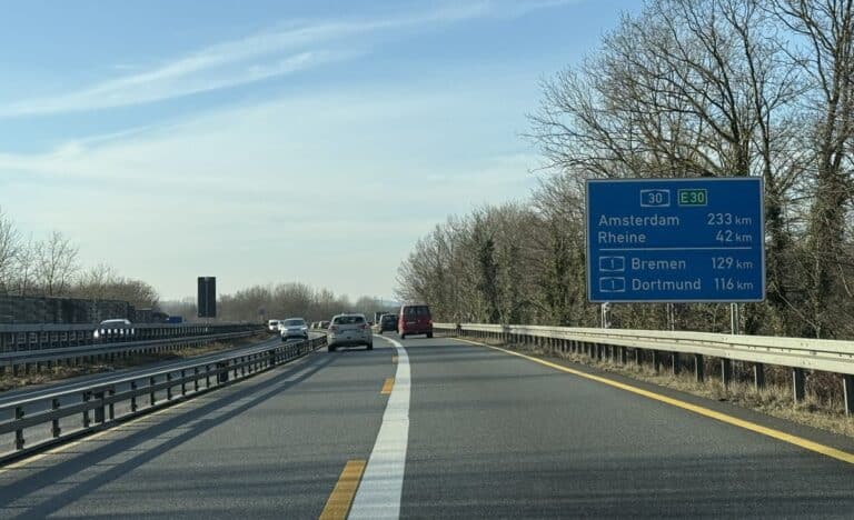 Autobahn A30 bei Osnabrück-Hellern mit Autos und blauer Entfernungstafel nach Amsterdam, Rheine, Bremen und Dortmund