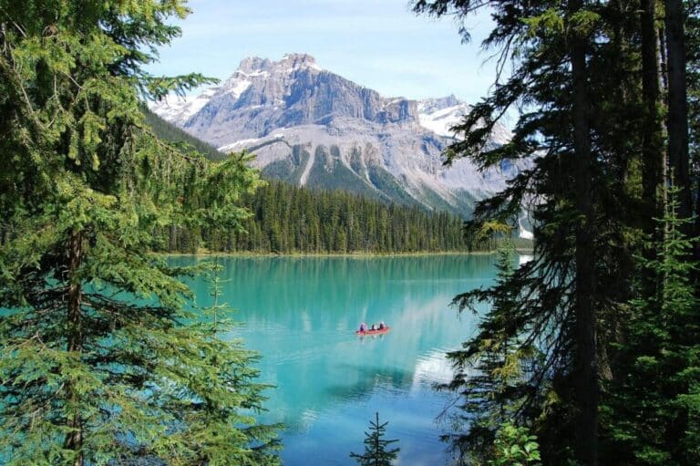 Ein rotes Kanu auf einem türkisfarbenen See in Banff, Kanada, eingerahmt von Kiefern