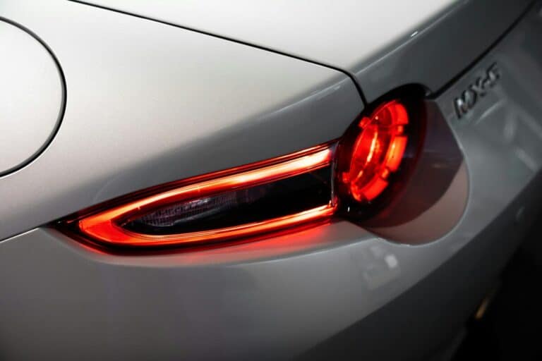 Rot leuchtende LED-Rückleuchte am Heck eines silbernen Mazda in Nahaufnahme