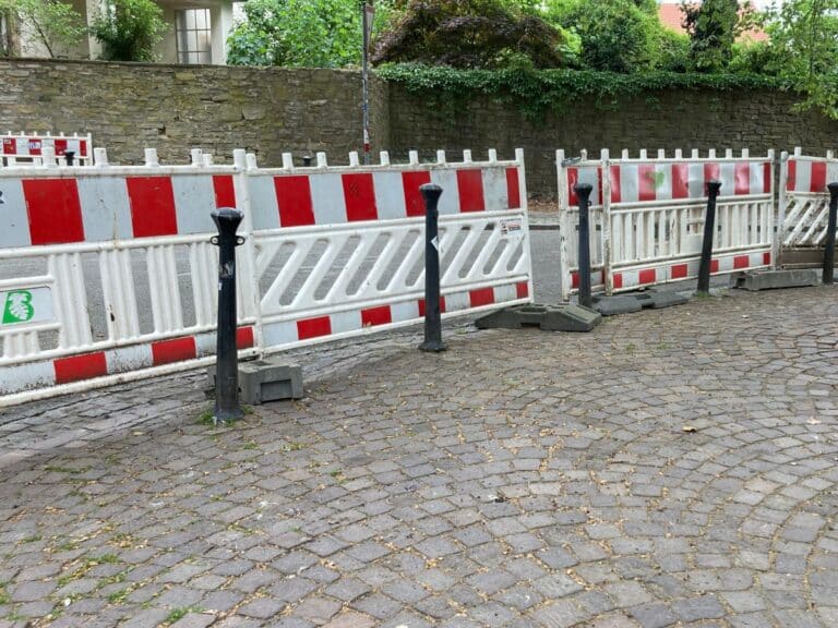 Rot-weiße Absperrgitter auf einer gepflasterten Straße
