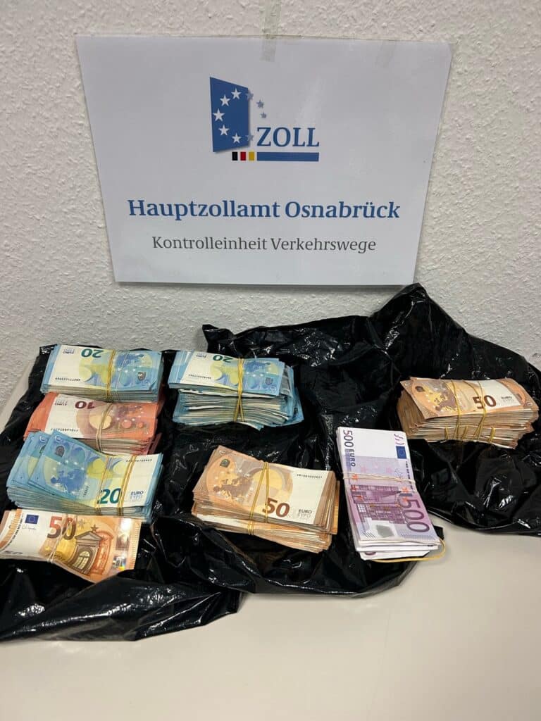 Bündel Euro-Scheine vor einem Schild des Hauptzollamts Osnabrück