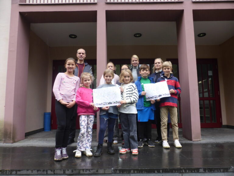 Schülerinnen und Schüler der Rückert- und der Elisabethschule präsentieren die frisch erarbeiteten Schulwegpläne zusammen mit (hinten von links) Malte Wanzek vom städtischen Team Mobile Zukunft, Miriam Spielberg-Siegel, Leiterin der Elisabethschule, und Stefanie Kohlmeyer, die die Rückertschule leitet. / Foto: Stadt Osnabrück, Yannik Kolmer