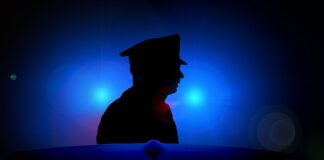 Silhouette eines Polizisten, dahinter Blaulicht