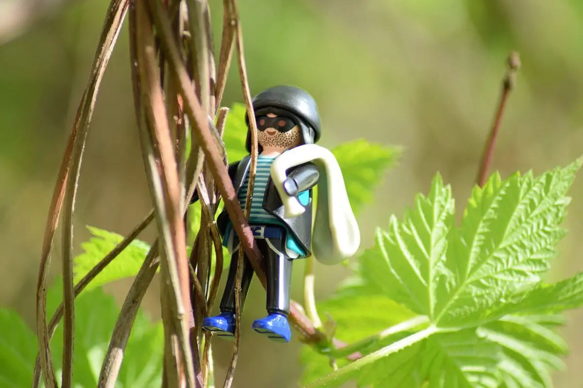Einbrecher zwischen Pflanzen im Garten, dargestellt durch eine Playmobilfigur (Symbolbild)