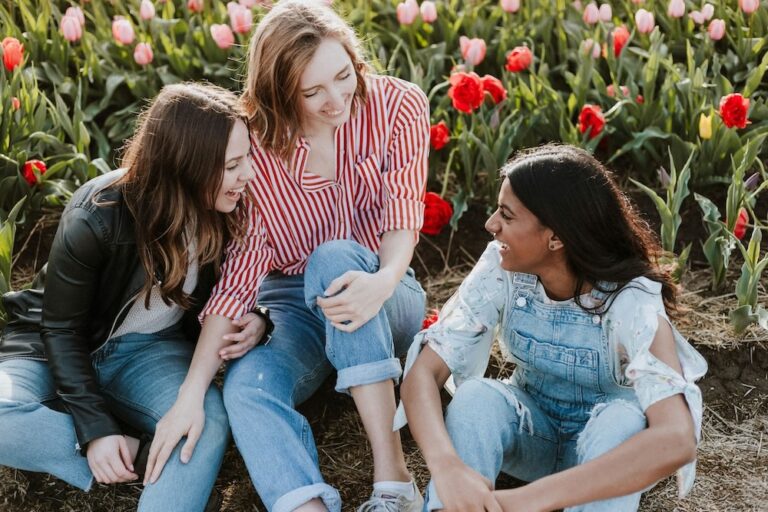 Drei junge Frauen auf einer Blumenwiese im Frühling.