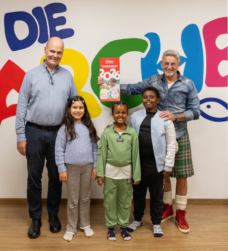 Freuen sich über den bisherigen Erlös des Kalenderverkaufs (v. l. n. r.): André Philipps (Geschäftsführer der Thomas Philipps GmbH & Co. KG), Kinder der Arche und John McGurk (Vereinsgründer Sportler 4 a childrens world e.V.) / Foto: Die Arche