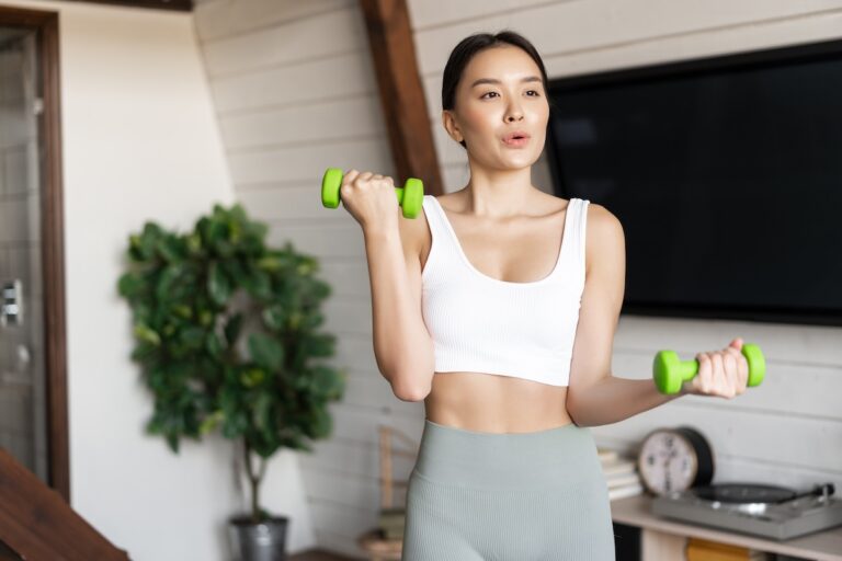 Frau im Fitnessstudio mit Hanteln beim Training