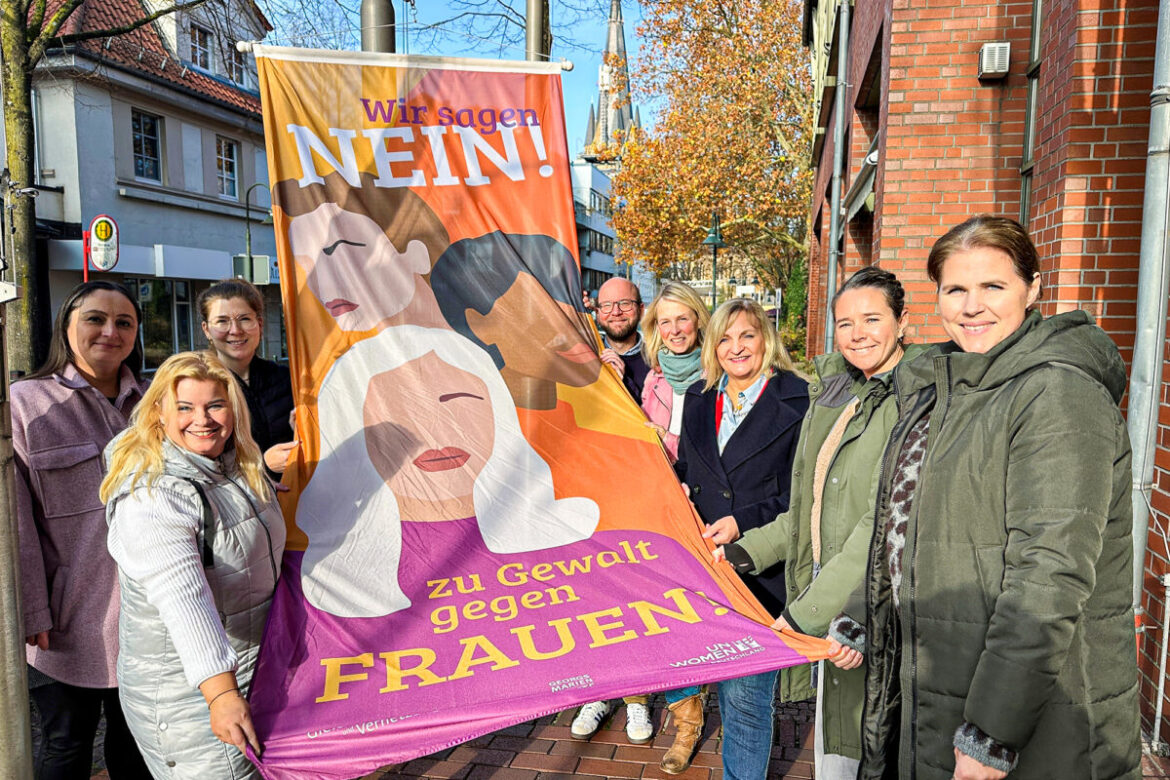 Gemeinsam mit Bürgermeisterin Dagmar Bahlo sowie Vertreterinnen und Vertretern der Kindertagesstätten St. Johannes Vianney und St. Michael, der Lutherkirchengemeinde sowie der Stadtbibliothek Georgsmarienhütte hat die Gleichstellungsbeauftragte Susanne Häring (vorne links) die Antigewalt-Flagge vor dem Rathaus gehisst.