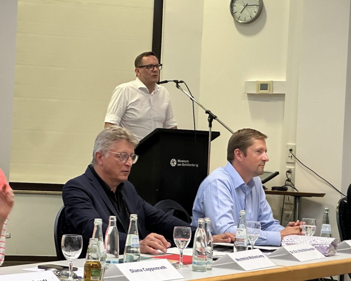 Rechtsanwalt Joë Thérond am Pult und davor Dr. Fritz Brickwedde und Philipp Bruelheide