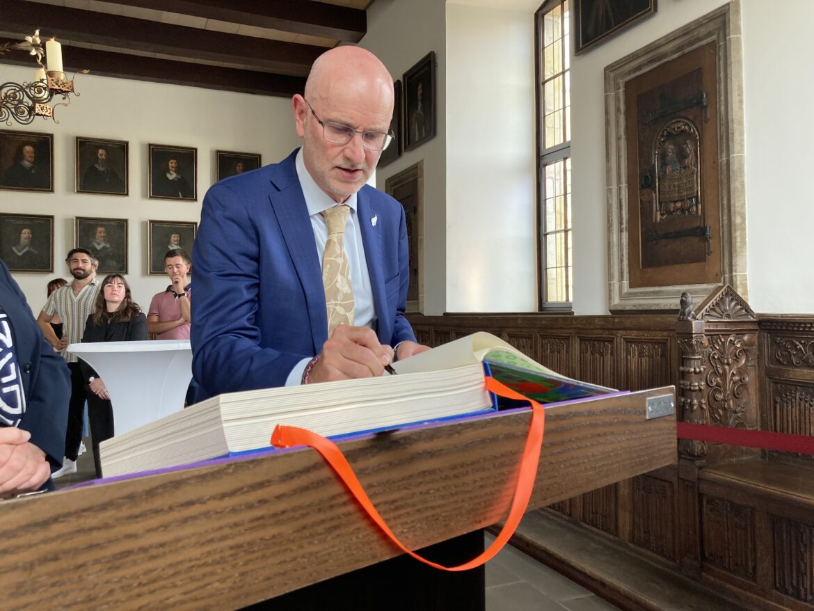 Neuseelands Botschafter in Deutschland, S. E. Craig Hawke, trägt sich - auf Deutsch - ins Goldene Buch ein. / Foto: Dominik Lapp