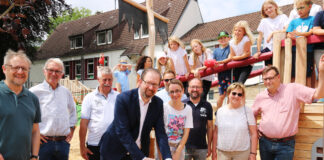 Zur Freigabe des neuen Spielgeländes schnitt Erster Stadtrat Alexander Herzberg mit Vertreterinnen und Vertretern aus Politik und Verwaltung, der Schulleitung sowie den Ortsbotschafterinnen und Ortsbotschaftern des Stadtteils Harderberg symbolisch ein rotes Band durch.