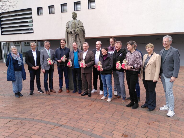 Vertreter der Sparkasse und den Osnabrücker Schulen vor der Statue Karls des Großen auf dem Schulhof des Carolinums.
