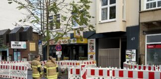 Feuerwehrleute warten darauf, dass die Kontrolle eines Hauses im Evakuierungsgebiets abgeschlossen ist
