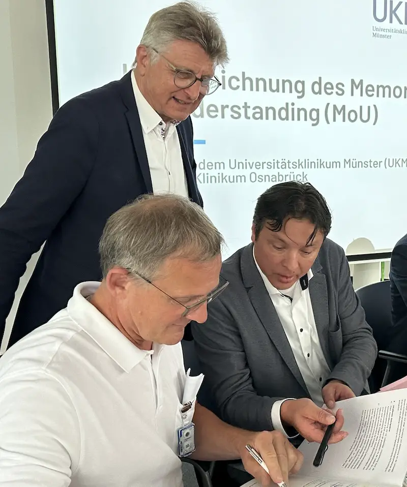 PD Dr. Peter Teschendorf, Dr. Fritz Brickwedde (hinten) und Klinikum-Geschäftsführer Frans Blok setzen ihre Unterschrift unter das MoU