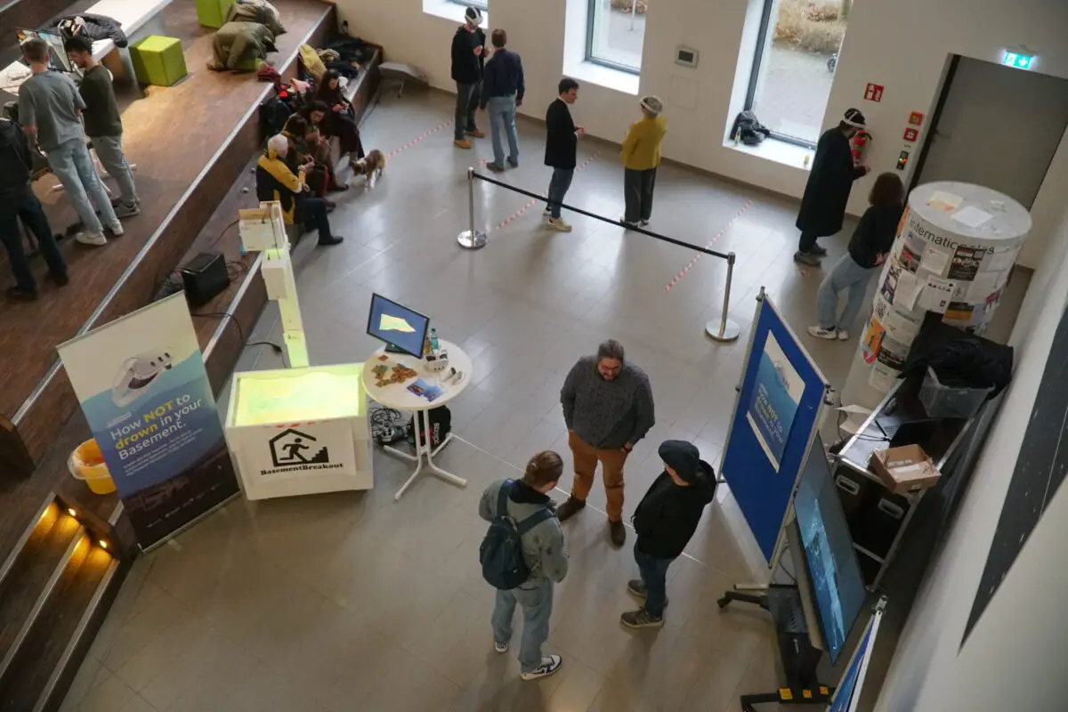 Wie Osnabrücker Studierende eine VR-Simulation gegen Starkregen-Gefahren entwickeln Projektstand von GROWTH bei der Messe "Lösungen für die Welt von morgen" an der Hochschule. Hinter der Bande ist das VR-Areal zu sehen.