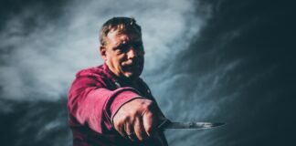 Mann hält Messer drohend vor sich