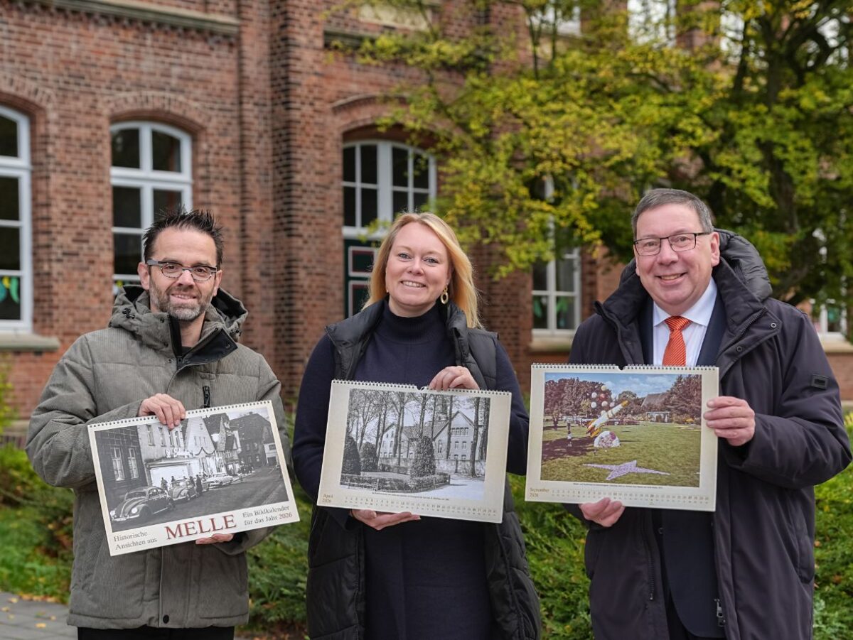 Vor der Kulisse der Grönenbergschule in Melle-Mitte präsentieren (von links) Uwe Plaß, Jutta Dettmann und Jürgen Krämer den Bildkalender „Historische Ansichten aus Melle 2025“, der ab sofort im Handel erhältlich ist. / Foto: Niels Wagner