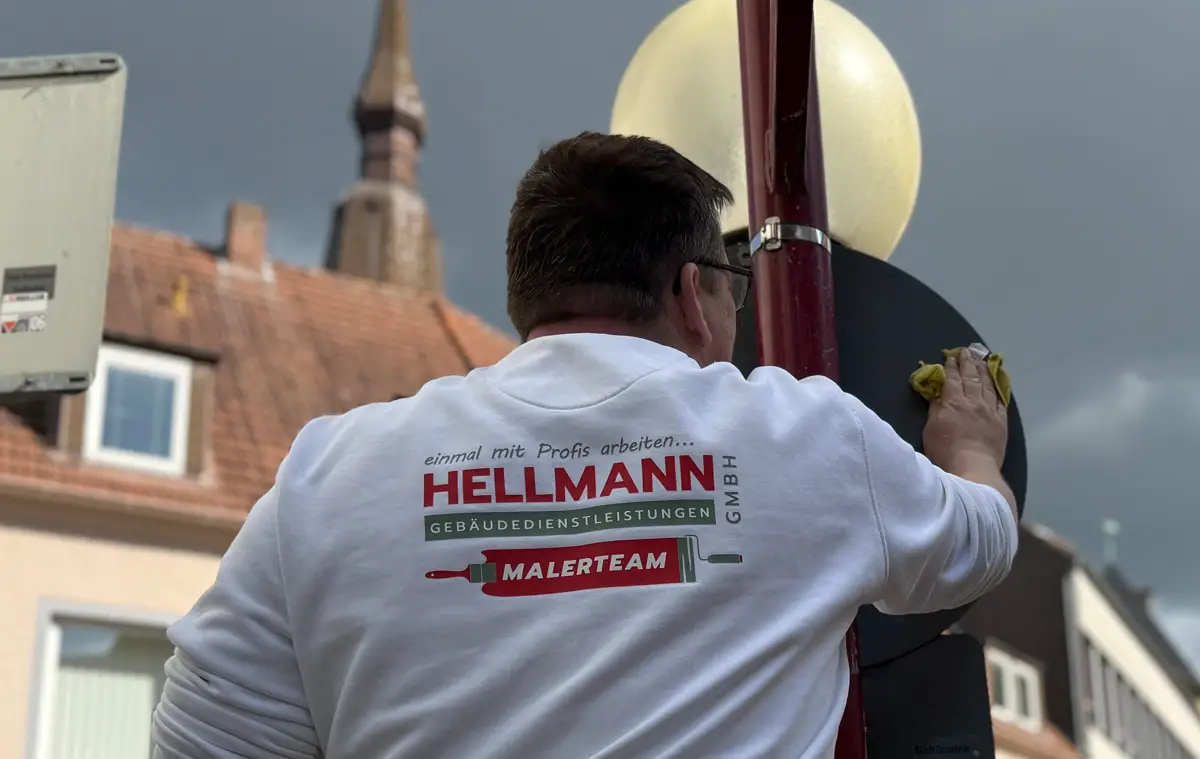 Ein Mitarbeiter einer Fachfirma entfernt Sticker von einem Straßenschild in der Osnabrücker Altstadt