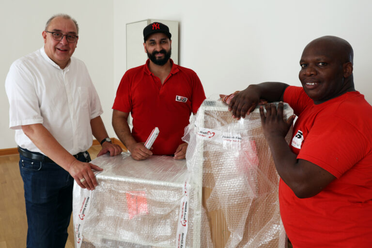 Bischof Dominicus mit zwei Mitarbeitern der Umzugsfirma beim Möbelauspacken.